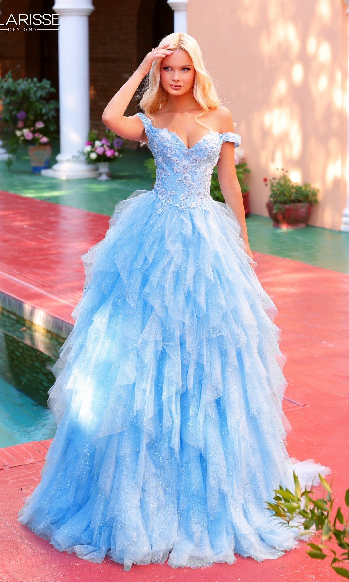 Outdoors, a woman wears the Clarisse Designs 62265 long prom dress in baby blue, featuring an off-the-shoulder bodice, floral lace accents, and a ruffled tulle skirt.